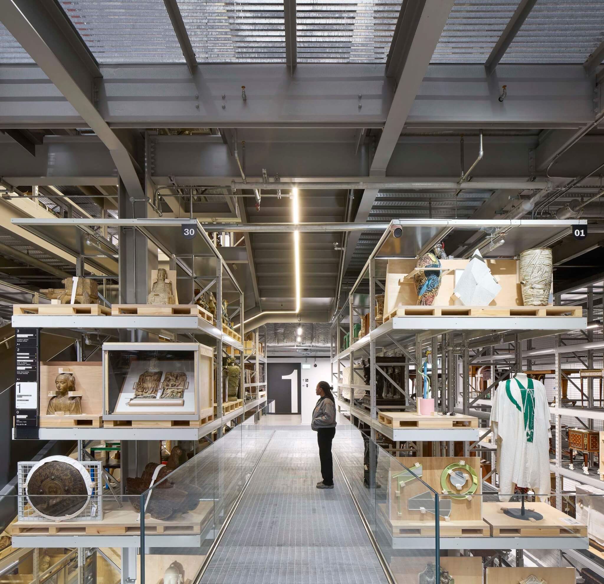 person standing amid shelves with museum objects inside the v&a east storehouse