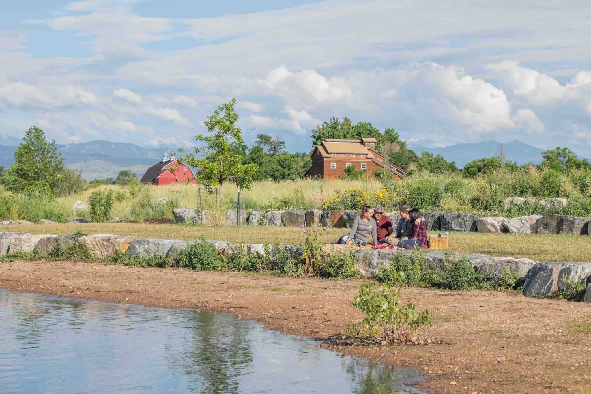 Photo of lake, farmland, barn, with people picnicking.