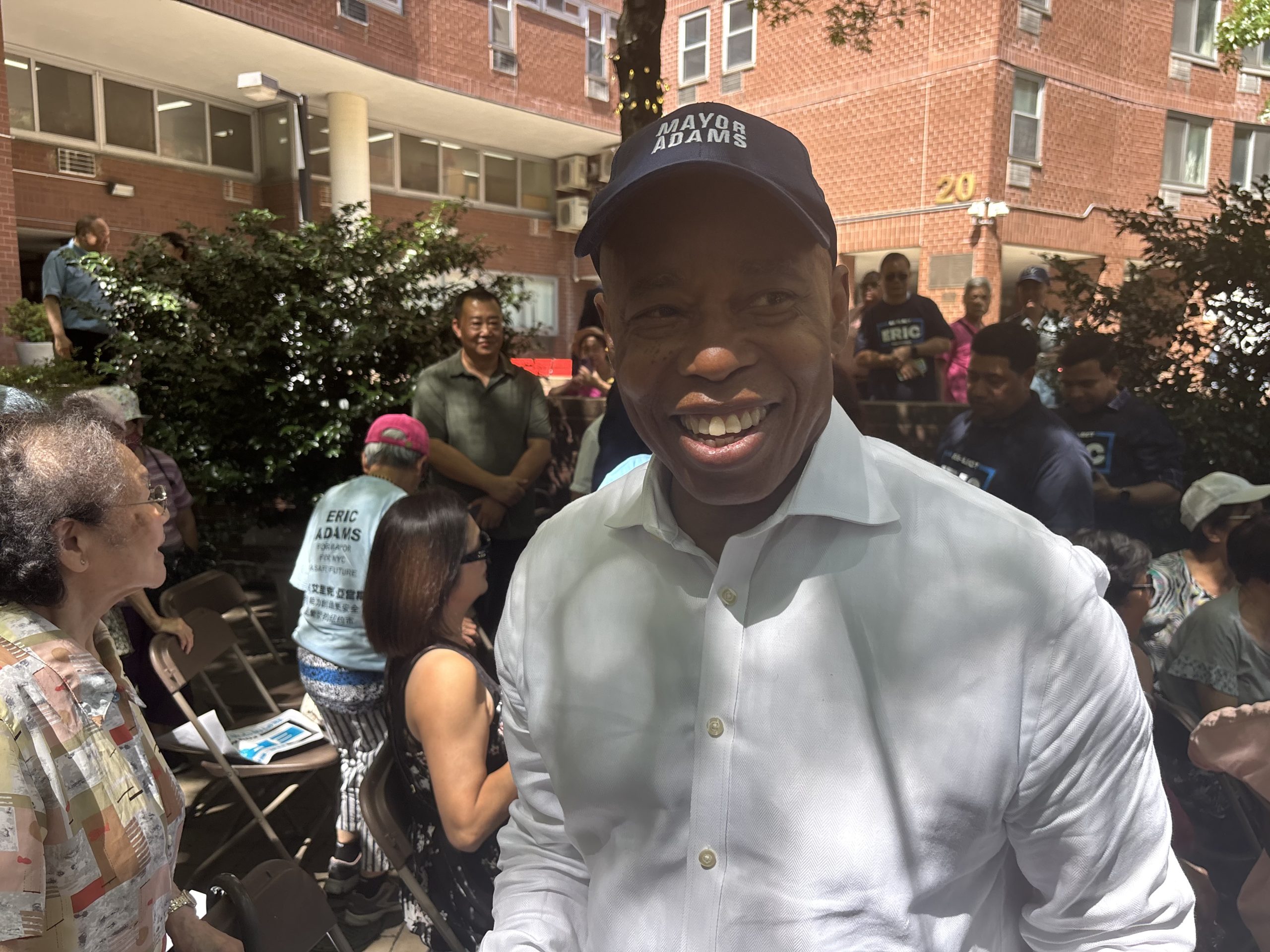 Eric Adams, smiling, wears a hat reading