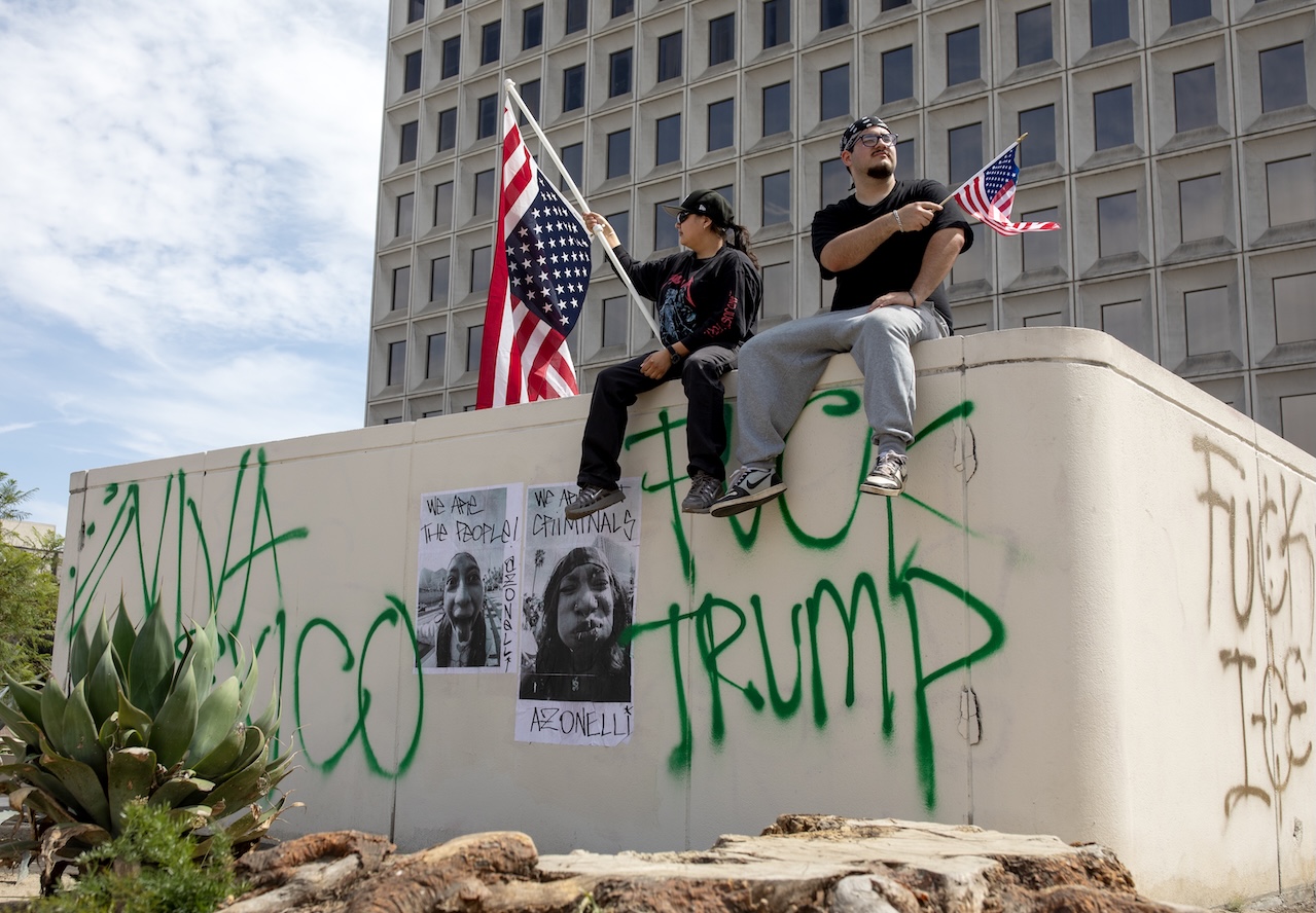 Two protesters on a graffiti-covered wall during the 