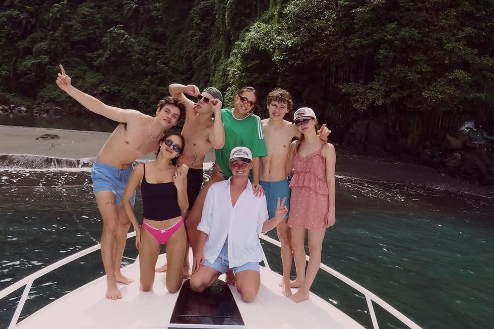 group of people posing on the bow of a boat with a tropical background