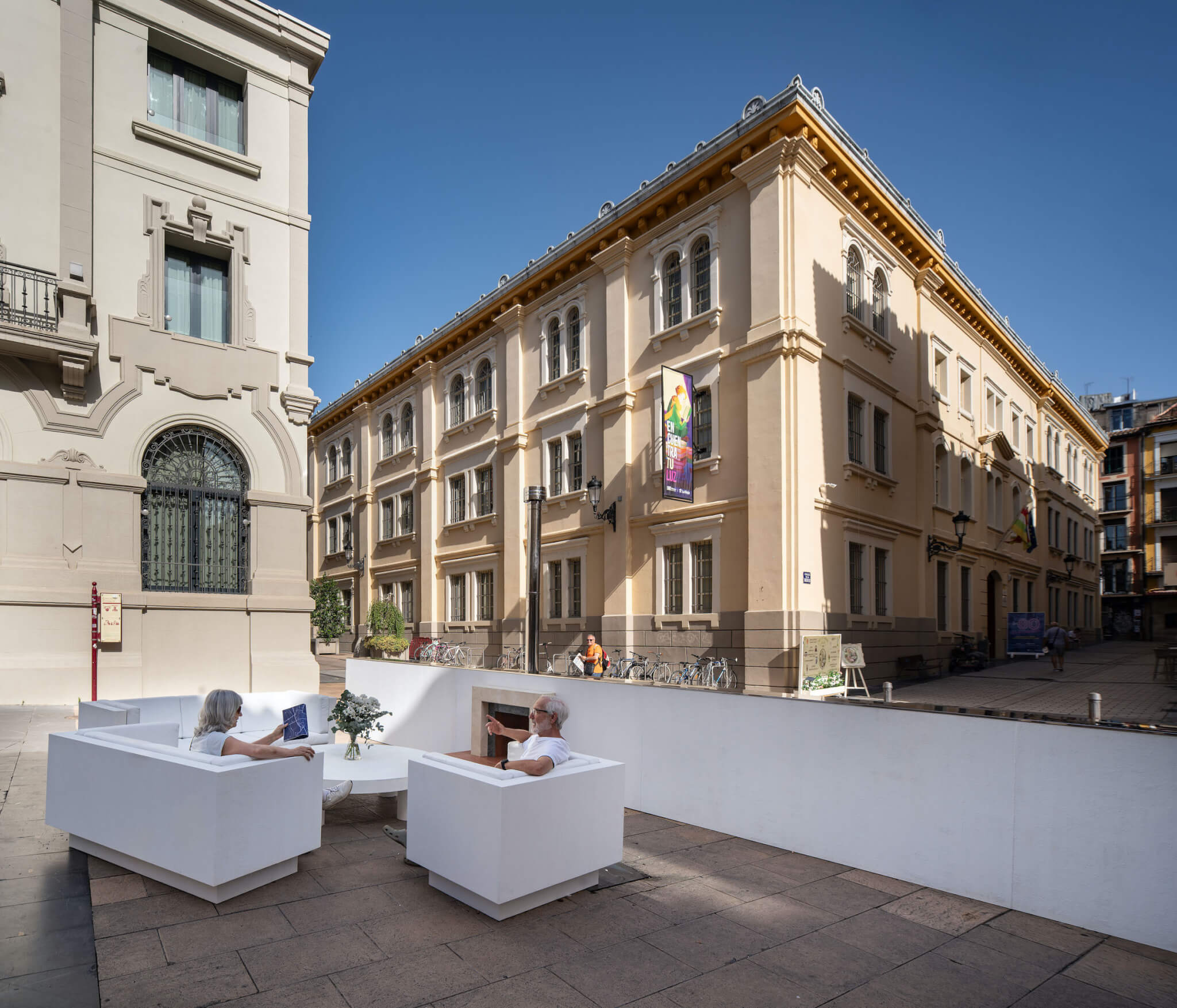 at Concentrico Plaza with art installation comprising of a white wall wit a fireplace and white sofas.