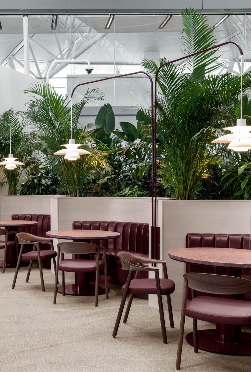 Oxblood-coloured booth seating with lush planting behind