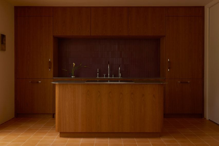 Kitchen featuring cherry millwork, which surrounded oxblood-red tiles and stainless steel counters