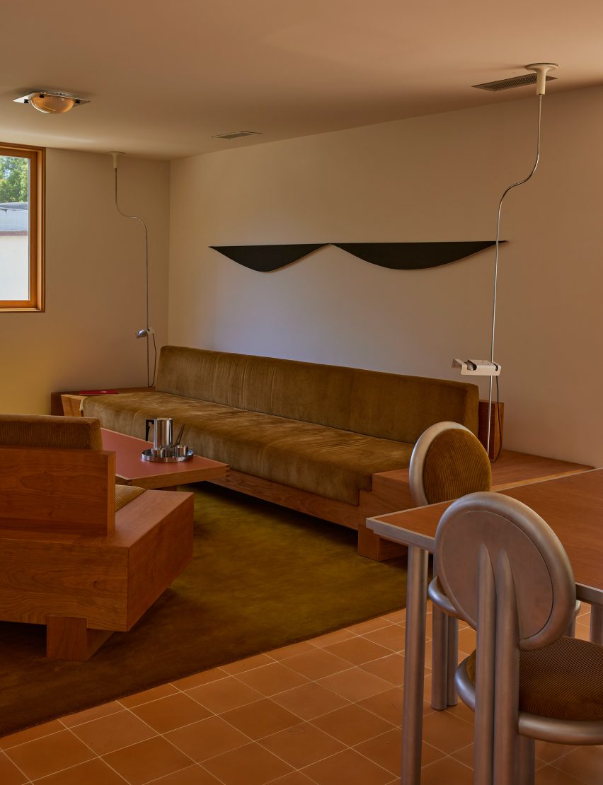 Lounge featuring cherry wood furniture, orange cement floor tiles and stainless steel dining chairs