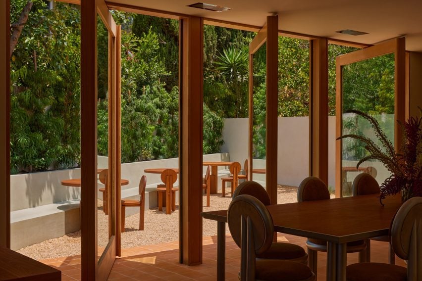 Large glass panels pivoted open onto a verdant courtyard
