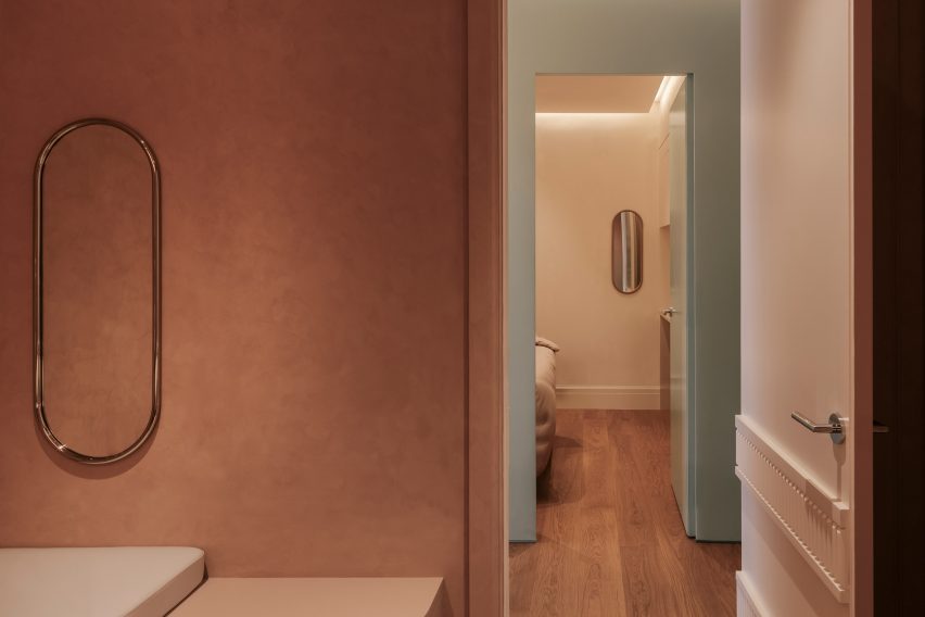 Treatment room with an earthy palette, looking out to a corridor accented in a glossy mint-toned finish