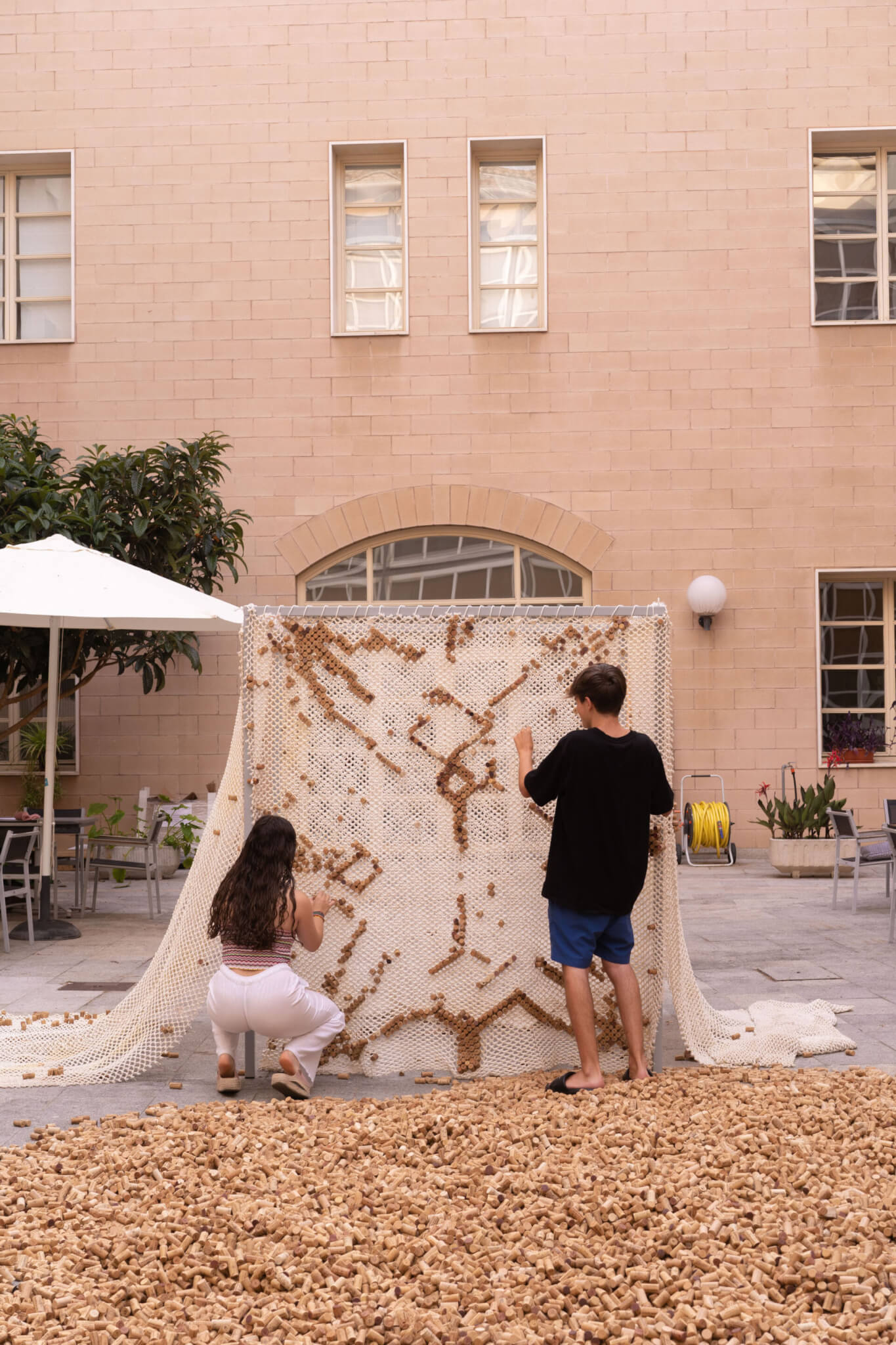 two people adding corks to a net to create a design
