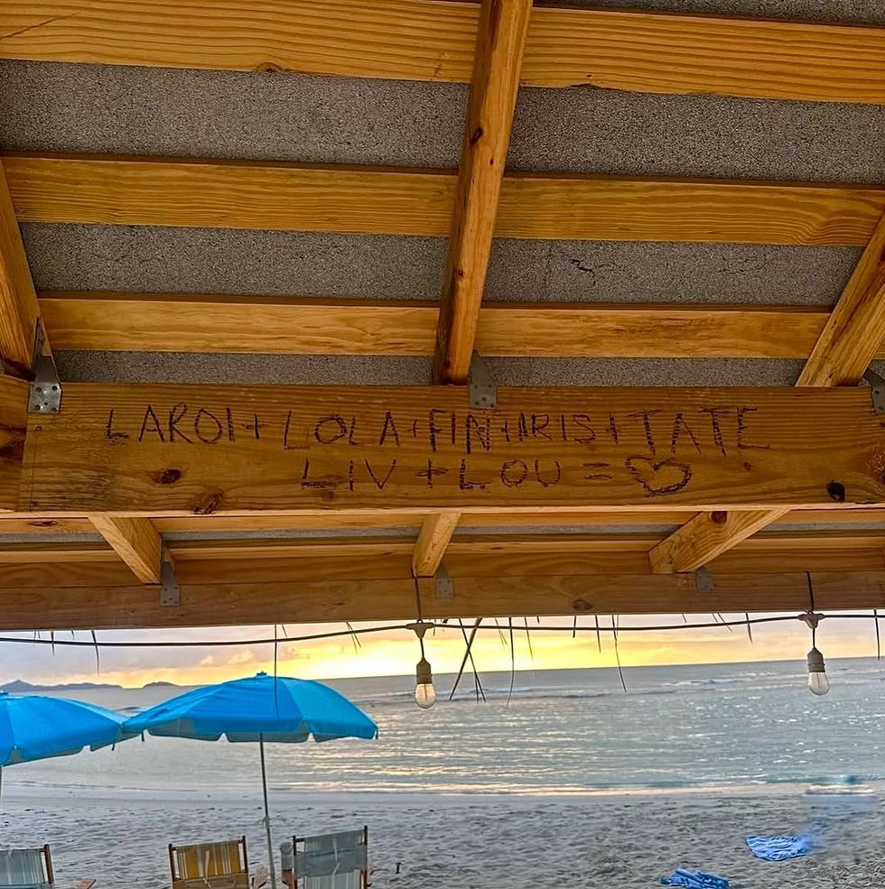 graffiti on a wooden beam displaying names and a heart symbol