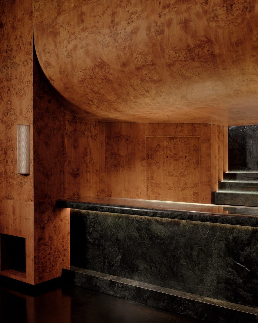 Dark green stone bar with burl wood veneer panelling above and around
