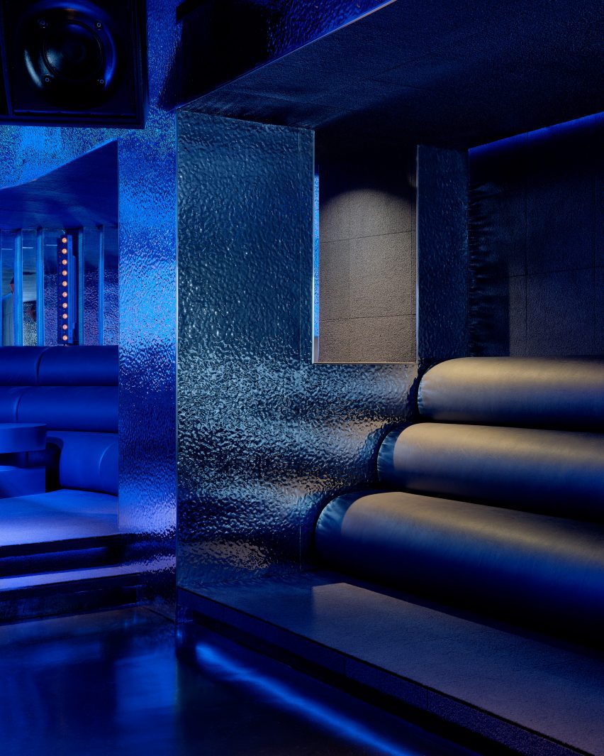 Tubular leather seats fill a niches and wrap in an arc behind a DJ booth