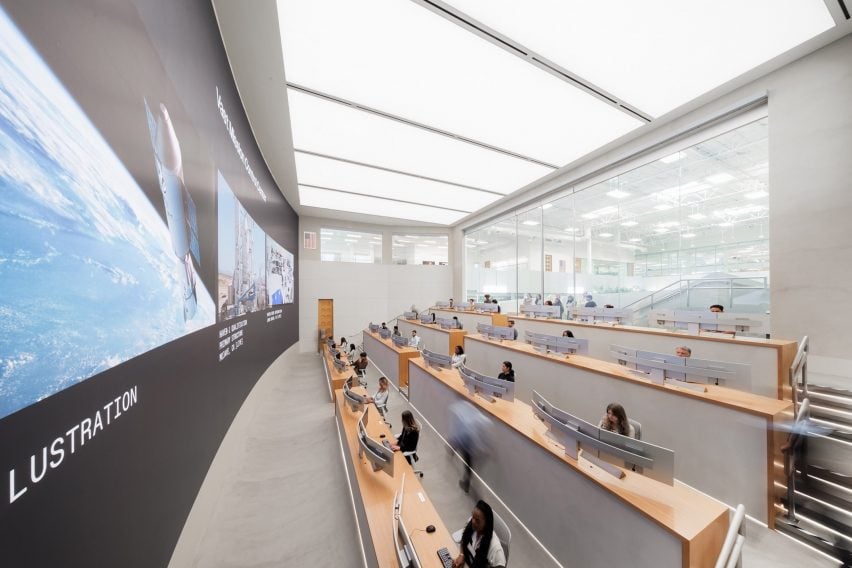 Photo within the mission control centre of the Vast space company, showing personnel sitting at long desks behind wide multi-screen setups with a giant floor-to-ceiling, wall-to-wall screen in front of them showing graphics of rockets and space
