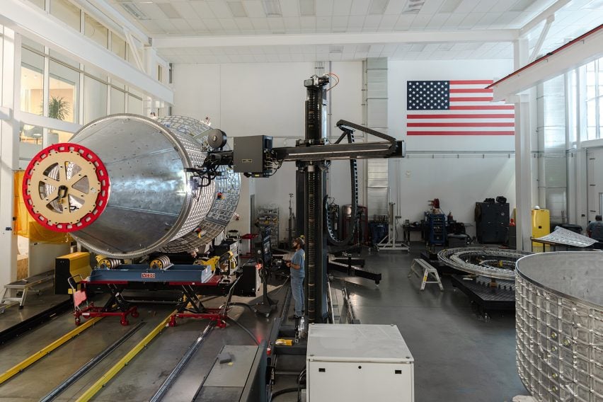 Photo of the clean room at Vast's Long Beach headquarters, showing a space station module being fabricated on the floor and an American flag on the wall