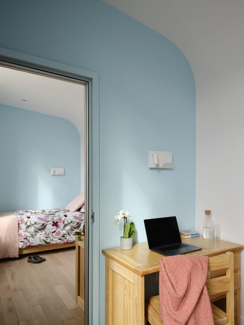 Bedroom with light blue walls, a bed and a small wooden desk