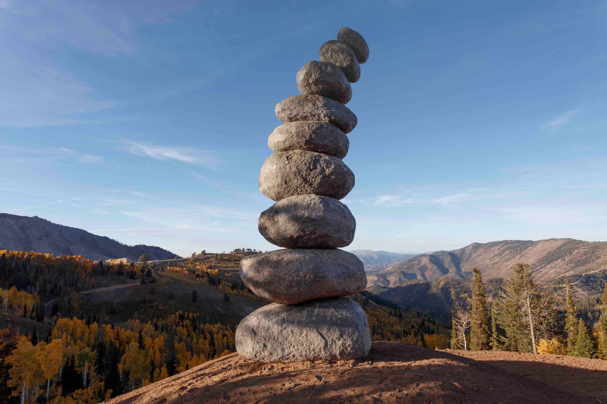 Sculpture of stacked rocks with mountain in the background.