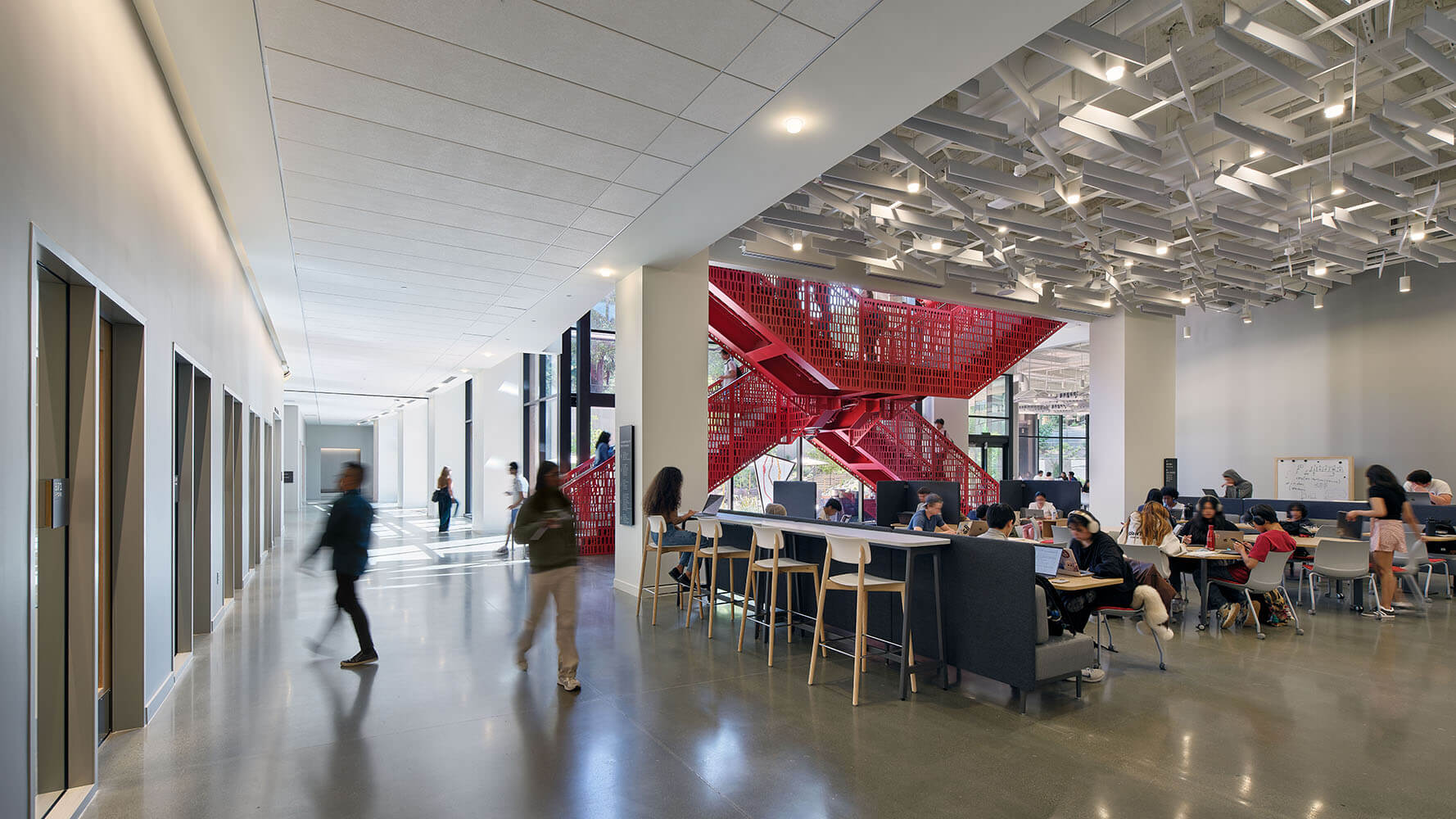 Interior view of building with student lounge and red staircase.