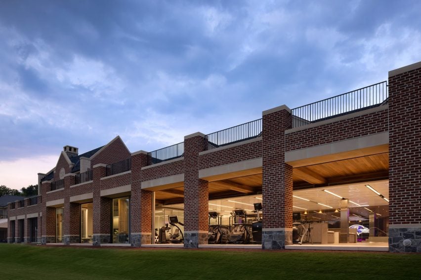 Exterior of a brick building with columns in front of a long glass wall