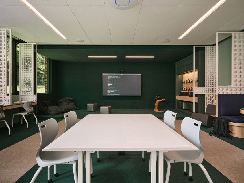 Classroom with minimalist decor, green walls and a central white table