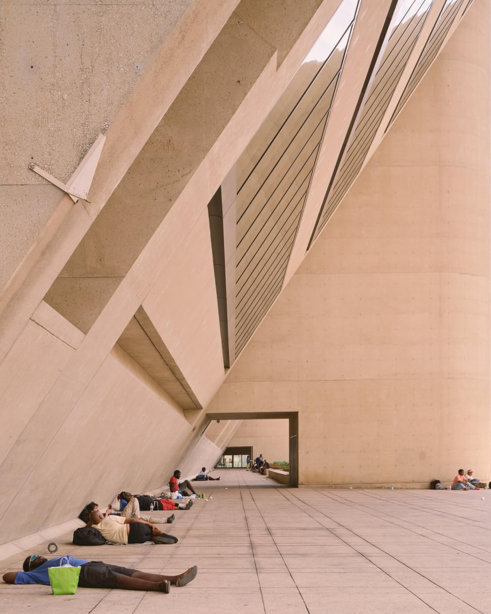 People laying in the shade of Dallas City Hall