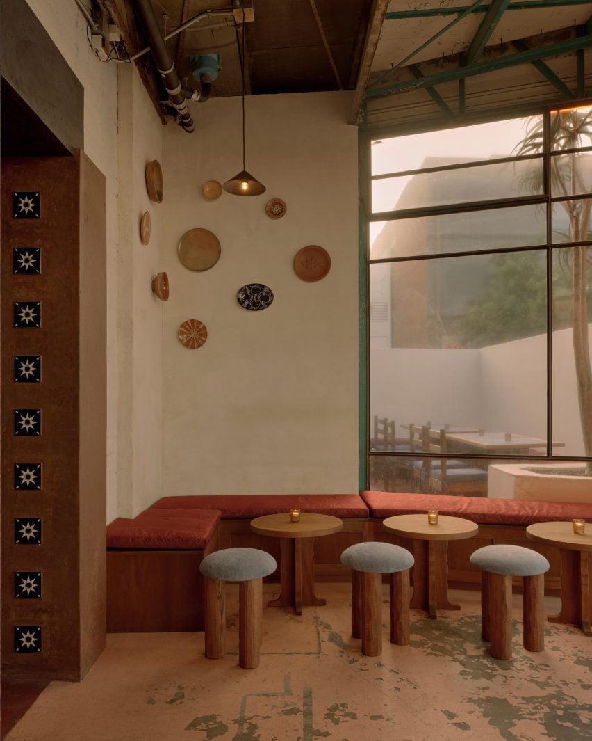 Bench seating and stools below a wall display of ceramic plates