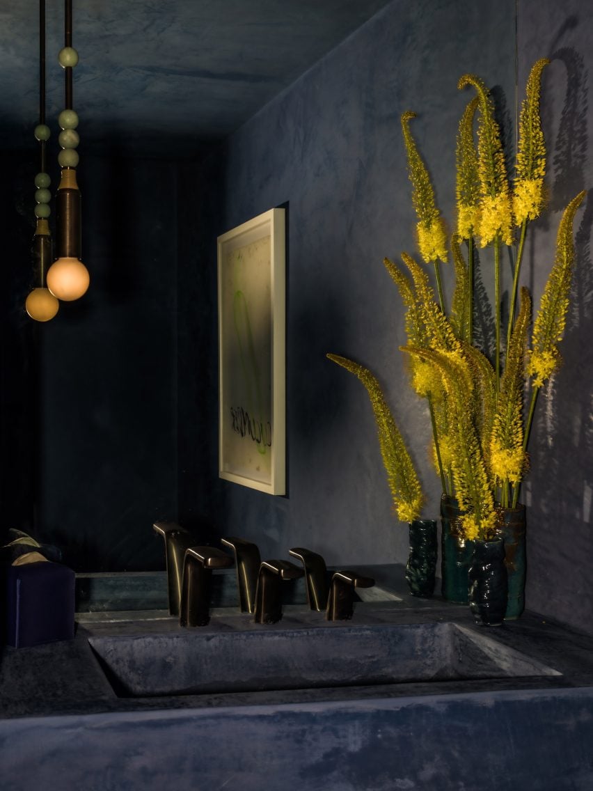 Bathroom decorated in deep blue with yellow flowers beside the sink