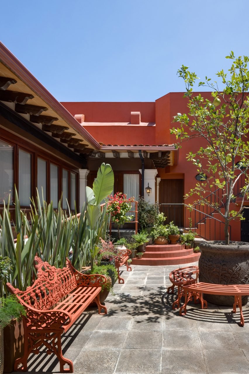 Courtyard of a red house with red park benches and planting