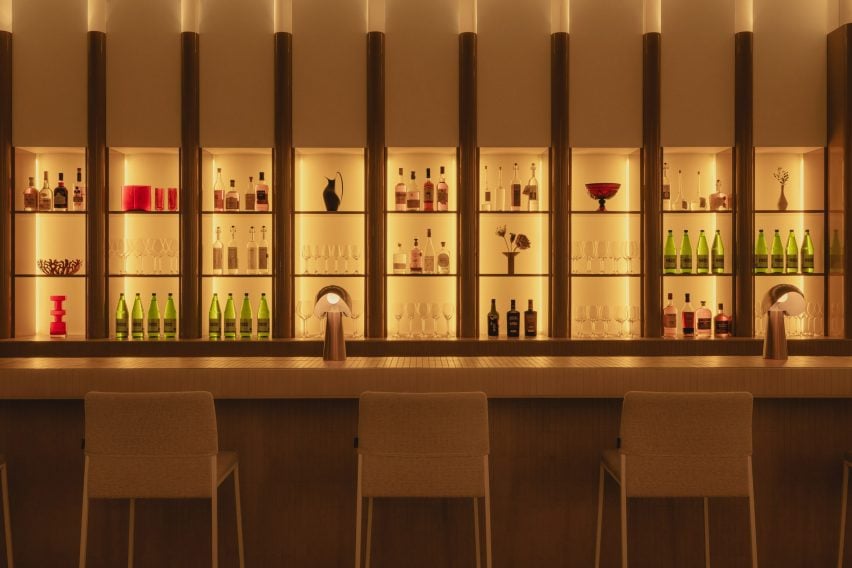 Fluted glass divides a grid of glowing niches behind a bar