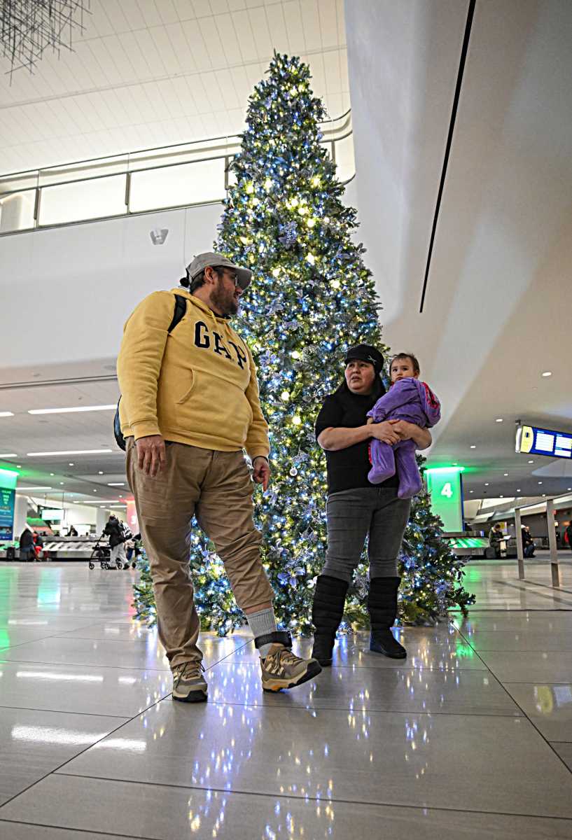 Queens family standing in front of a sparkling Christmas tree