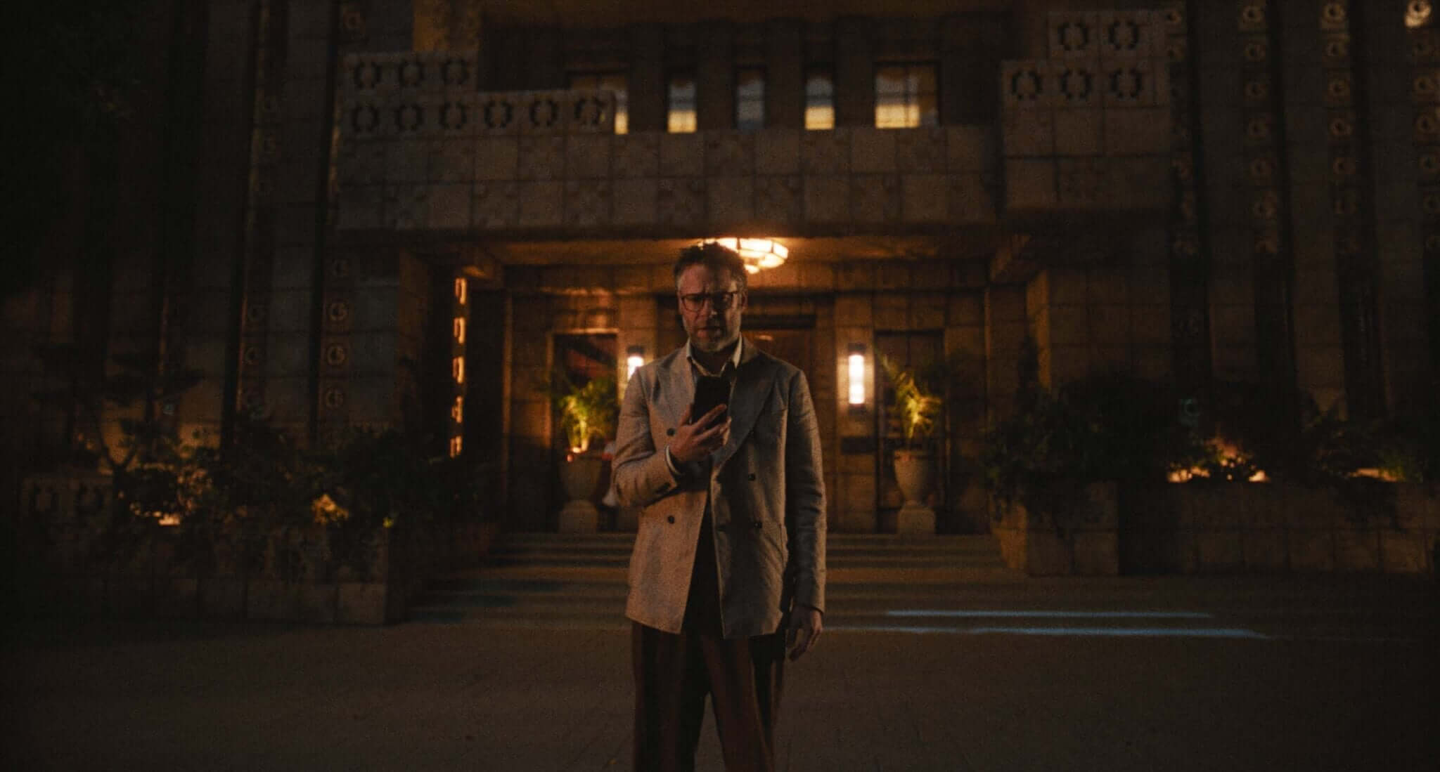 Seth Rogan looking at his phone with a building in the background