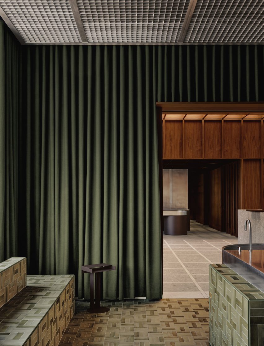 Room with dark green curtains over the walls and metal grating installed across the ceiling