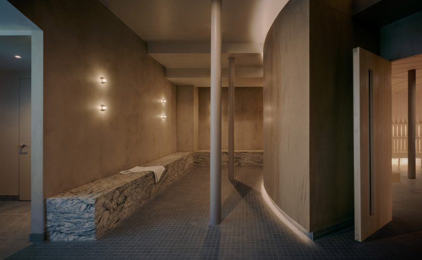 A seating area before a sauna, featuring marble blocks and textured plaster walls