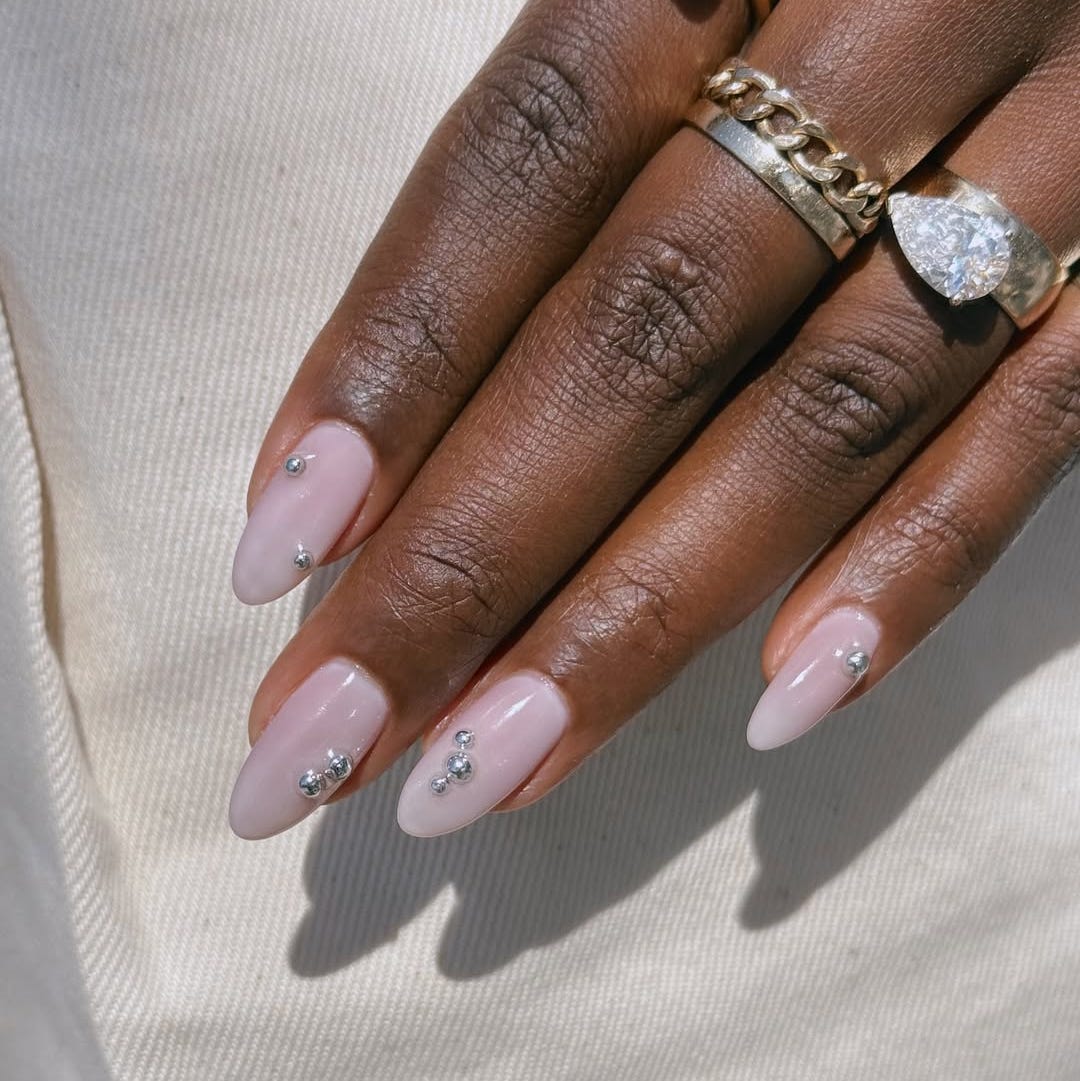 manicured hand with light pink nails and decorative embellishments