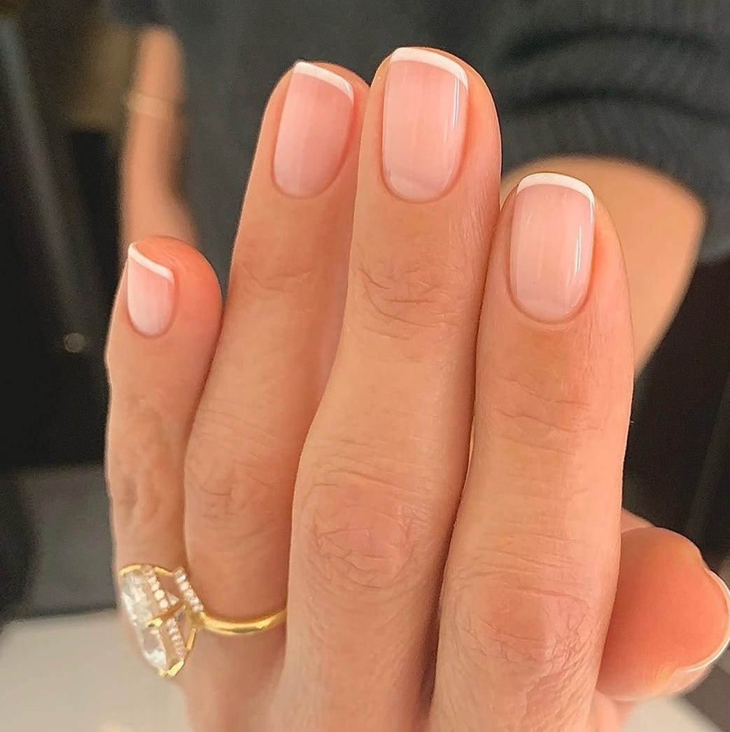 closeup of wellgroomed nails with a french manicure and a gold ring
