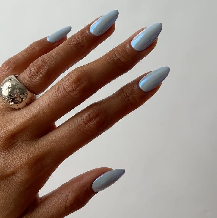 hand with long light blue nails and a silver ring