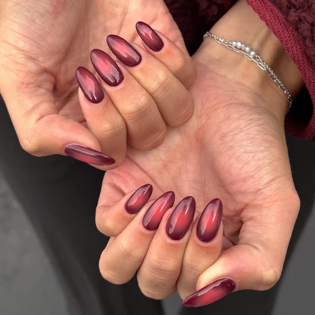 a closeup view of manicured hands showing long ovalshaped nails with a gradient maroon color